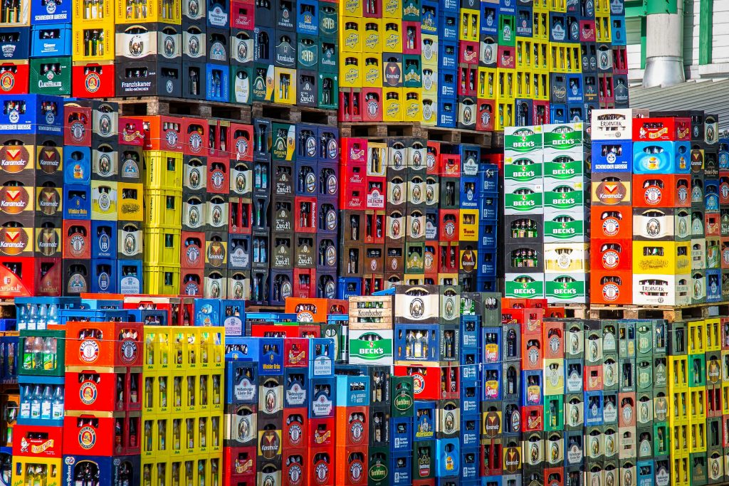 Services A vibrant display of beer crates stacked in a warehouse, showcasing various brands.